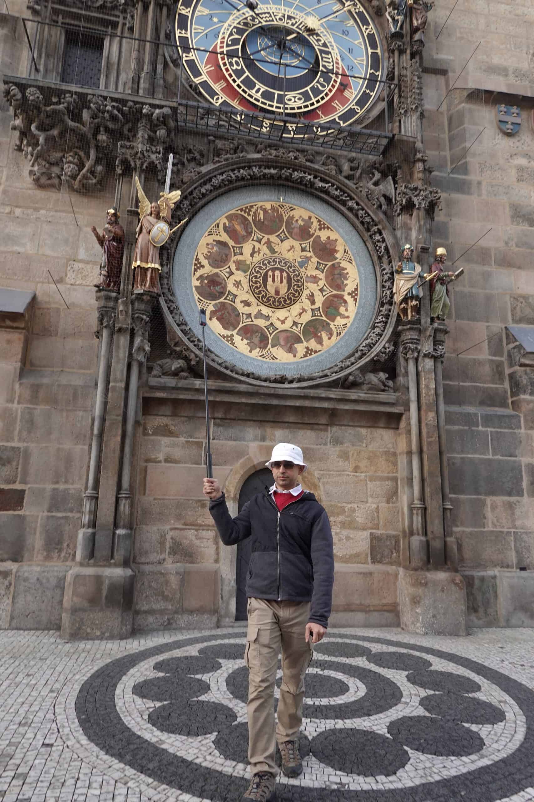 Filming with my 360 camera above my head on a selfie stick : Me casually walking away while filming Prague astronomical clock with my Insta360 X3 while travelling.